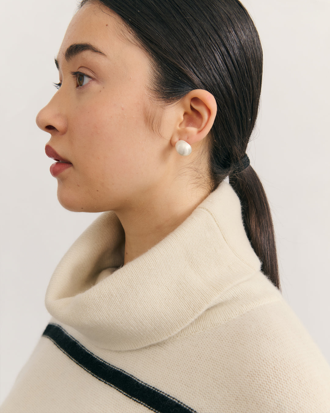 Detail shot of structured fold neck turtleneck collar on cream raw striped pure cashmere knit