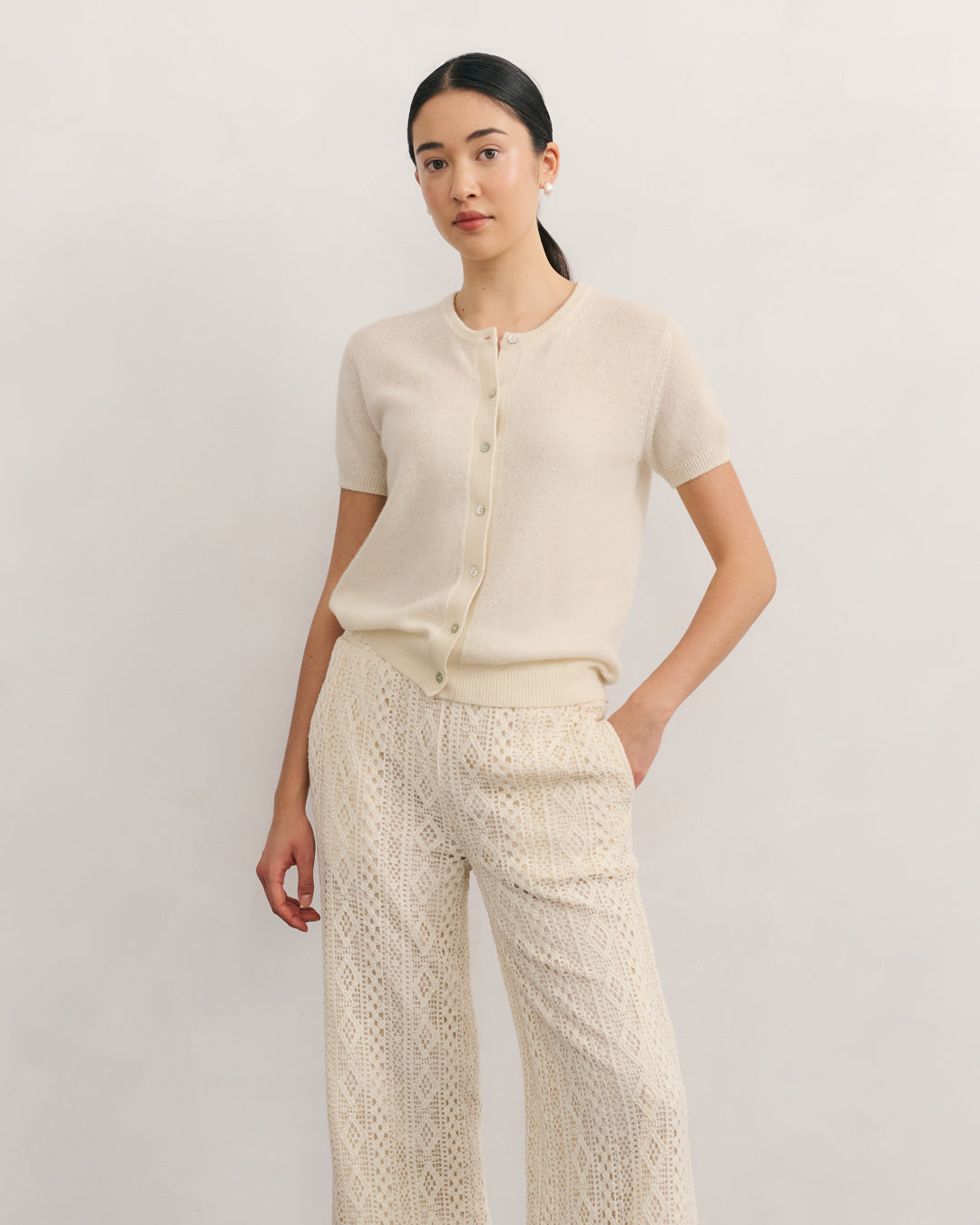 Cream 100% cashmere short sleeve cardigan with shell buttons, styled with lace trousers.