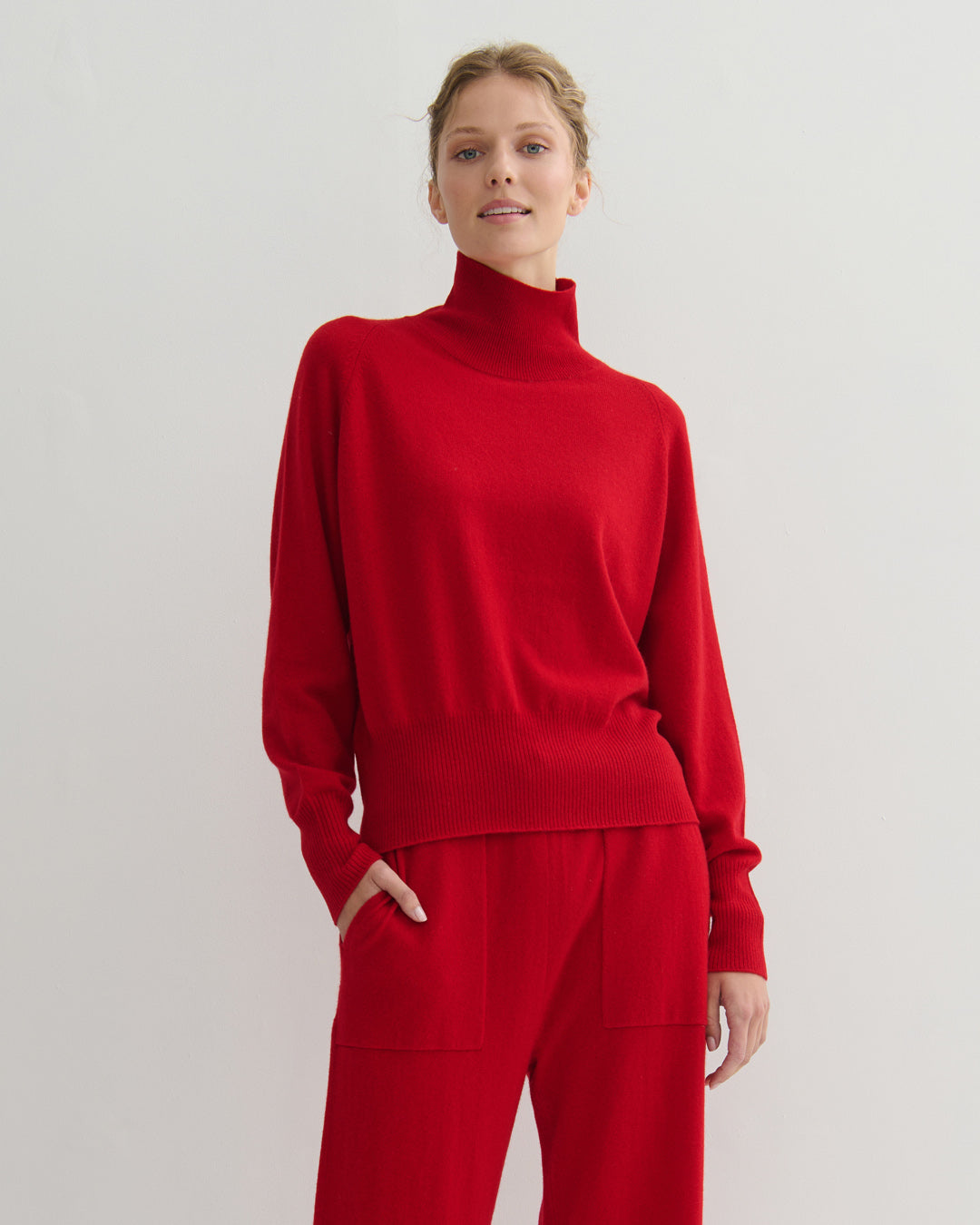 Model wearing a scarlet red mockneck cashmere sweater and pants